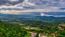 Wisatawan menikmati pemandangan hijau pegunungan Indonesia dari balik jendela lebar kereta api eksekutif yang nyaman.