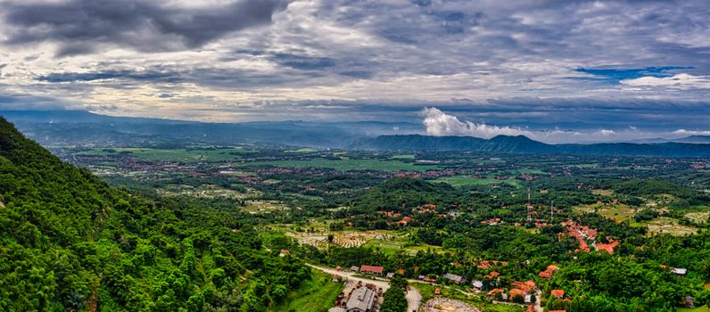 Wisatawan menikmati pemandangan hijau pegunungan Indonesia dari balik jendela lebar kereta api eksekutif yang nyaman.
