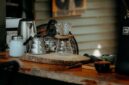 Seorang warga Desa Adat Kemiren menyeduh kopi tradisional menggunakan cangkir tanah liat di tengah suasana pedesaan Banyuwangi yang asri.