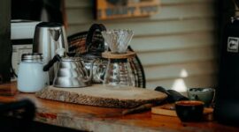 Seorang warga Desa Adat Kemiren menyeduh kopi tradisional menggunakan cangkir tanah liat di tengah suasana pedesaan Banyuwangi yang asri.