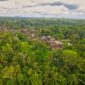 Seorang pelancong menikmati pemandangan perbukitan hijau sembari berinteraksi dengan warga lokal di desa wisata kawasan lereng gunung.