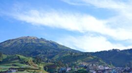 Penumpang menikmati pemandangan perbukitan hijau melalui kaca jendela besar di dalam gerbong kereta wisata panoramik yang melintasi Pulau Jawa.