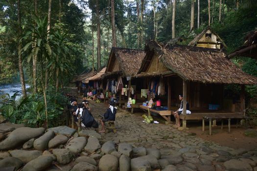 Seorang wisatawan menikmati keindahan arsitektur rumah adat dan interaksi hangat bersama masyarakat lokal di desa wisata berbasis lingkungan kawasan Sumba.
