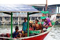 Sebuah perahu kayu penyeberangan melaju membelah perairan jernih di kepulauan Nusantara untuk mengantarkan para pelancong menjelajahi destinasi tersembunyi.