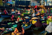 Seorang pelancong menikmati suasana tenang pedesaan di Flores sembari berinteraksi dengan warga lokal yang sedang mengolah kain tenun tradisional.