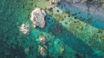 Pemandangan perairan jernih di Kepulauan Alor yang menjaga kelestarian terumbu karang dan mamalia laut melalui kearifan lokal masyarakat pesisir.