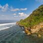 Pemandangan bukit hijau berlapis pantai perawan di wilayah kepulauan terpencil Indonesia yang menawarkan pengalaman wisata tenang jauh dari hiruk-pikuk perkotaan.
