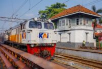 Penumpang menikmati pemandangan perbukitan hijau dari dalam gerbong kereta api pariwisata yang nyaman. Transportasi rel kini menjadi favorit pelancong yang menginginkan perjalanan santai tanpa terkendala kemacetan jalan raya.