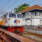 Penumpang menikmati pemandangan perbukitan hijau dari dalam gerbong kereta api pariwisata yang nyaman. Transportasi rel kini menjadi favorit pelancong yang menginginkan perjalanan santai tanpa terkendala kemacetan jalan raya.