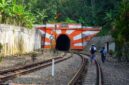 Wisatawan menikmati pemandangan perbukitan hijau dan persawahan dari balik jendela kaca lebar gerbong kereta wisata.