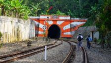 Wisatawan menikmati pemandangan perbukitan hijau dan persawahan dari balik jendela kaca lebar gerbong kereta wisata.