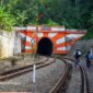 Wisatawan menikmati pemandangan perbukitan hijau dan persawahan dari balik jendela kaca lebar gerbong kereta wisata.