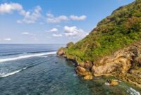 Pemandangan jalur jalan pesisir selatan Jawa yang membentang mulus di antara perbukitan kapur hijau dan lautan luas Samudra Hindia.