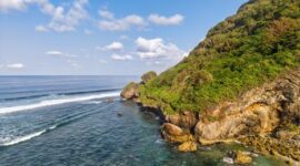Pemandangan jalur jalan pesisir selatan Jawa yang membentang mulus di antara perbukitan kapur hijau dan lautan luas Samudra Hindia.