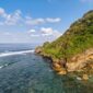 Pemandangan jalur jalan pesisir selatan Jawa yang membentang mulus di antara perbukitan kapur hijau dan lautan luas Samudra Hindia.