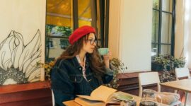 Seorang pelancong menikmati suasana pagi yang tenang di kedai kopi terbuka sembari merencanakan rute eksplorasi harian tanpa tergesa-gesa.